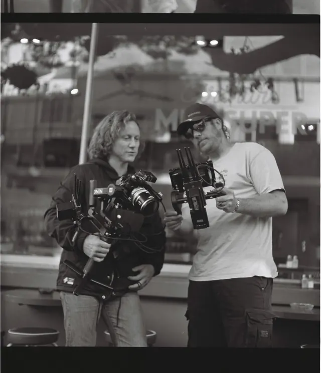 Two camera operators checking a gimbal rig, black and white